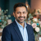 Portrait of a confident South Asian man smiling, representing a satisfied customer testimonial.