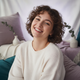 Headshot portrait of a smiling young woman, conveying trust and satisfaction.
